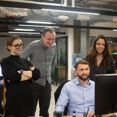 Four Global Lingo employees huddled around a computer smiling