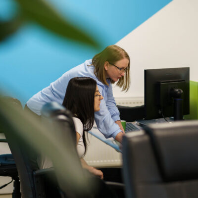 Two Global Lingo employees looking at a screen and working together