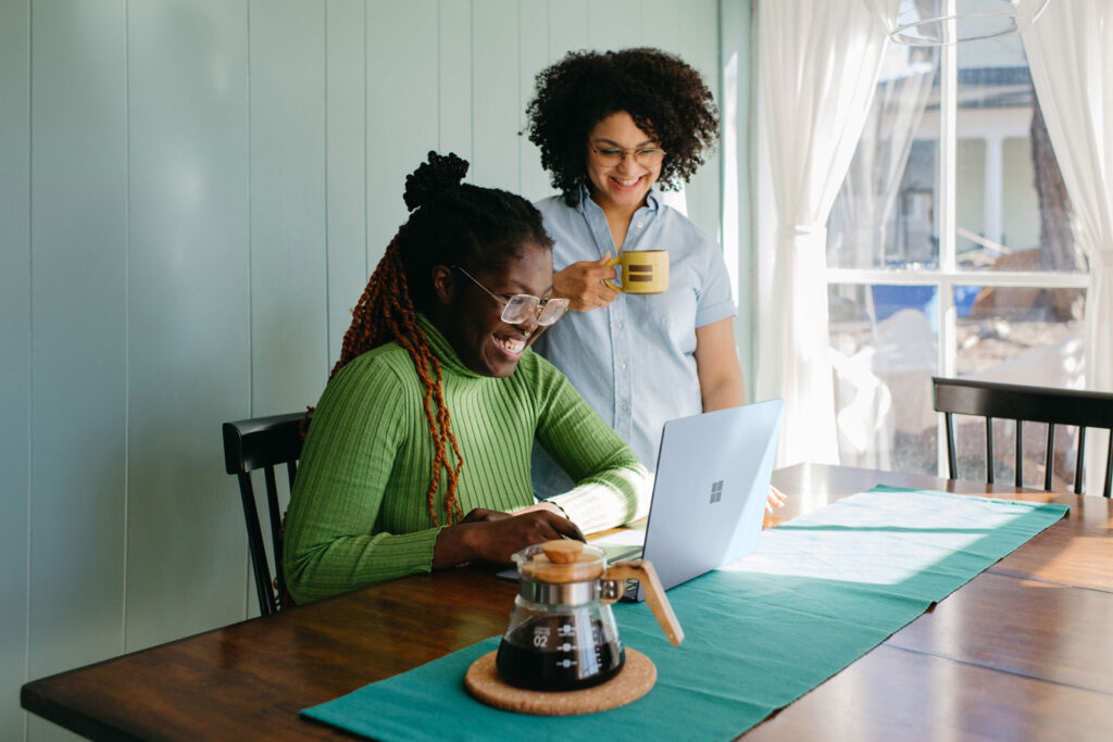 Two women smiling and looking at a laptop