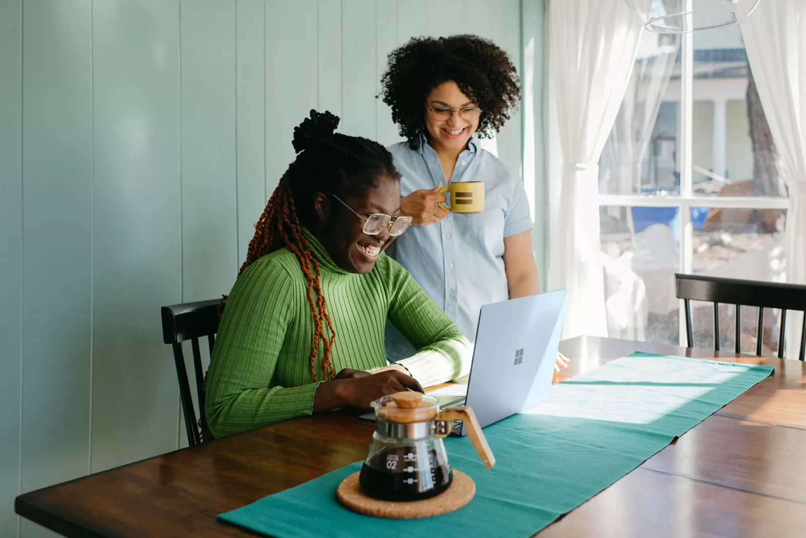 Two women smiling and looking at a laptop