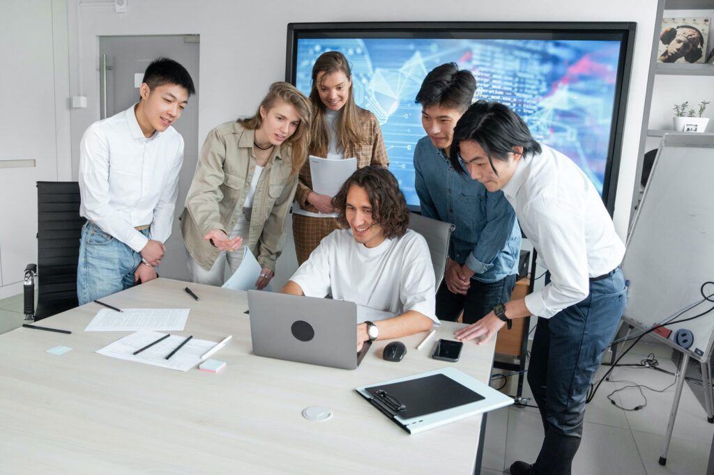 A group of employees standing around a laptop working on a project