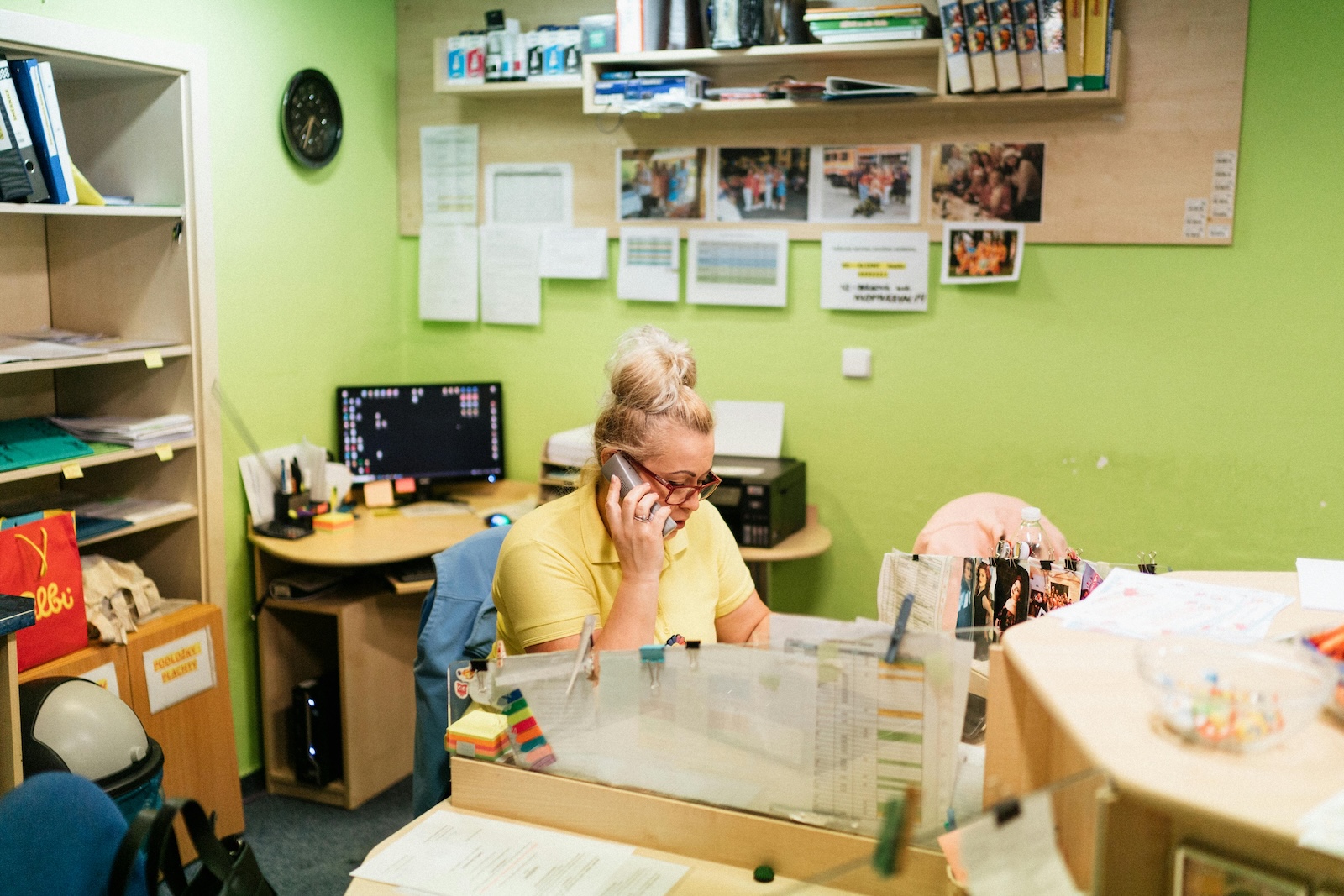 A health worker sitting in her office while holding the office phone in her right hand. She is trying to communicate to another person to relay important information.