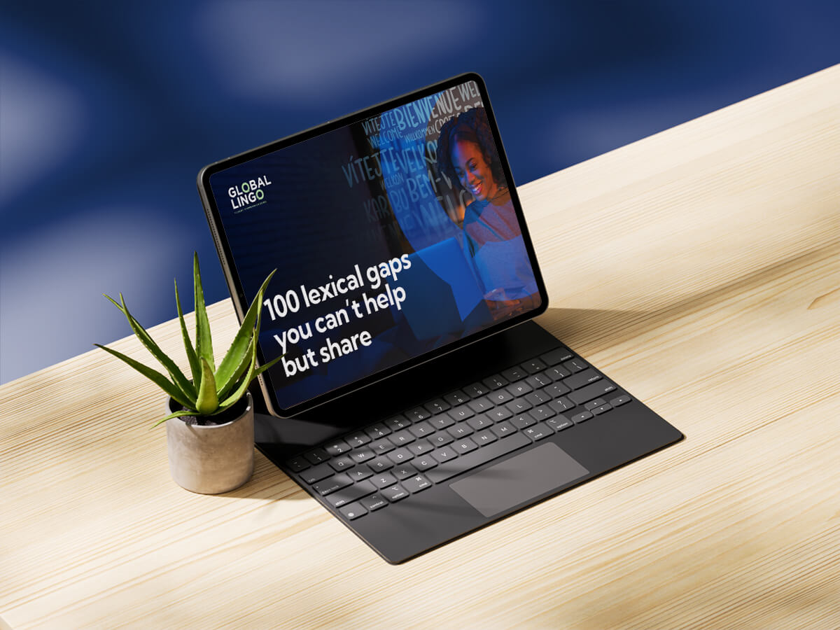 An iPad sitting on a desk next to a plant with our downloadable PDF on-screen titled '100 lexical gaps you can't help but share'. 