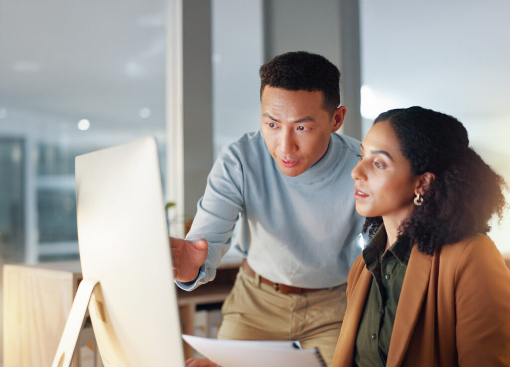 a male senior member of staff helping a female co worker on her computer