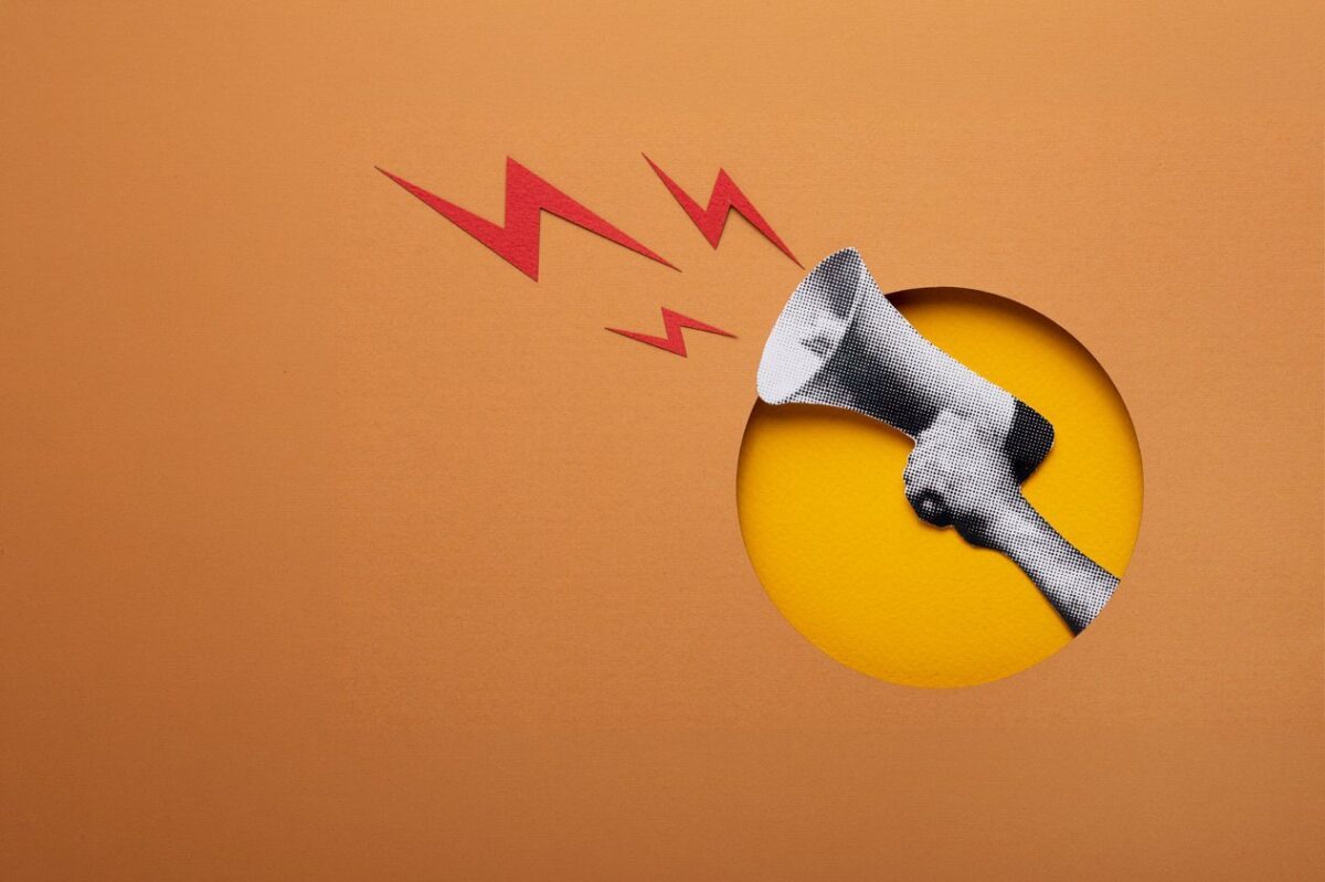 A paper-cut art style illustration of a hand holding a megaphone with red lightning bolts, representing powerful communication to overcome market research challenges