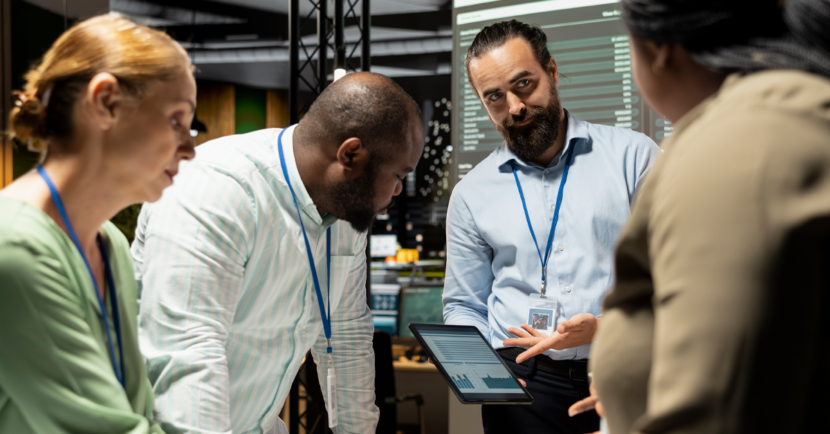 A collaborative team of professionals in a modern office reviewing data on a tablet to reduce friction across global operations