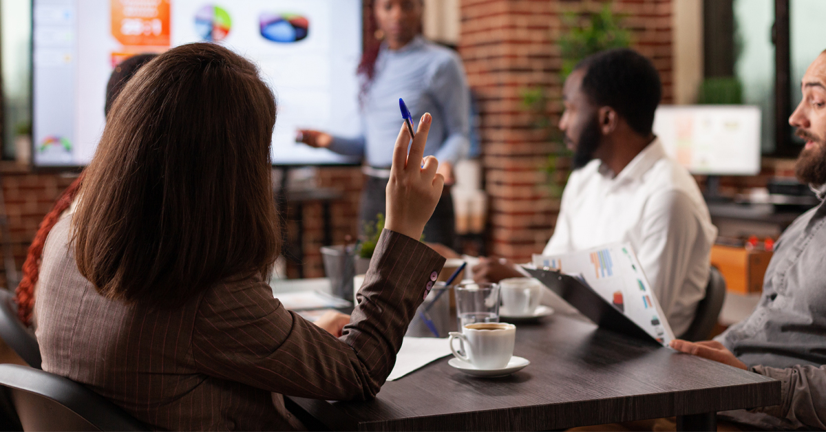 A group of professionals in a meeting room discussing data charts on a screen, demonstrating the final delivery of insights after solving complex market research challenges.