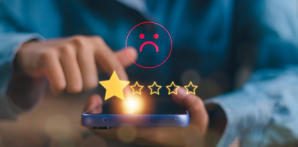 Close up of a person leaving a one-star review on a phone, highlighting the negative impact on travel demand trends when localization is ignored.