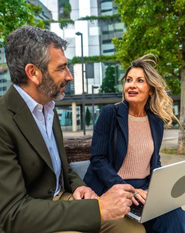 A professional man and woman having a business discussion with a laptop, showcasing Danish corporate language services