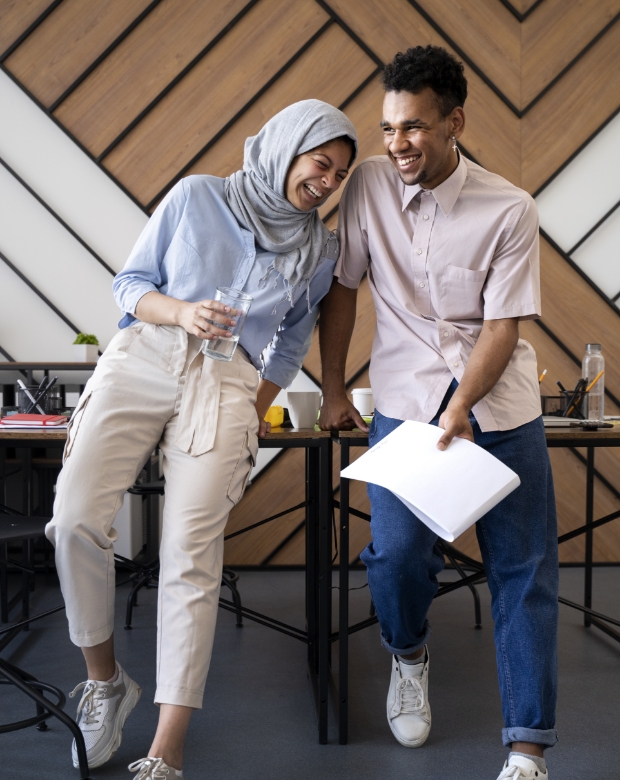 Two colleagues laughing and sharing documents in a modern office for Dari linguistic and cultural services