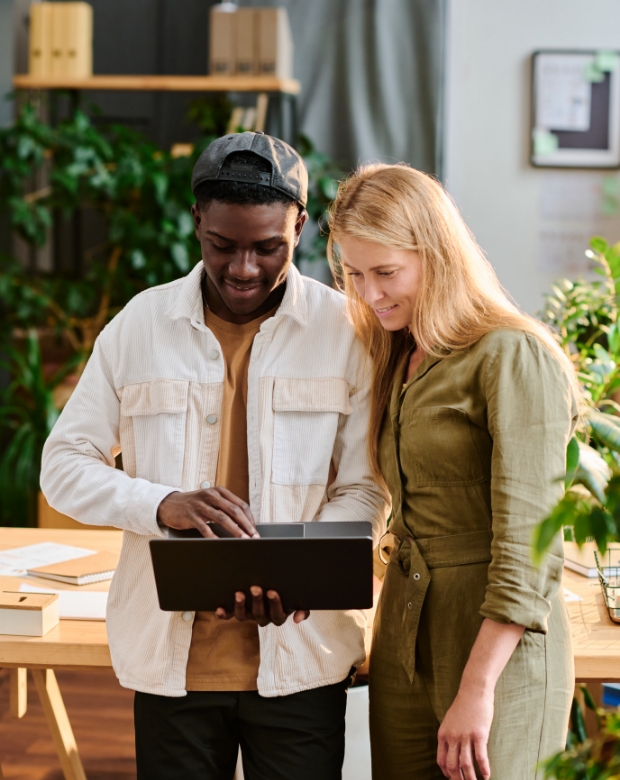 A professional duo analyzing data on a laptop screen for Finnish corporate language services