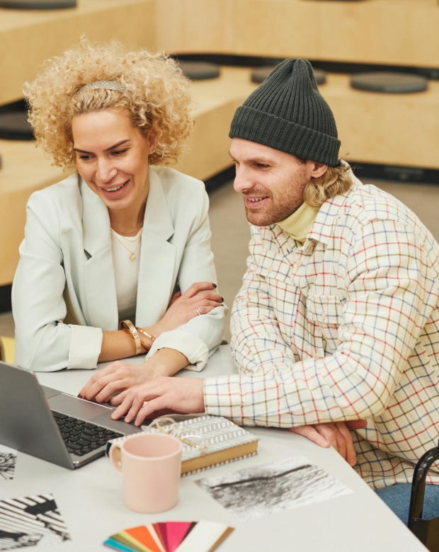 Colleagues collaborating on a laptop in a bright office, illustrating Lithuanian language solutions