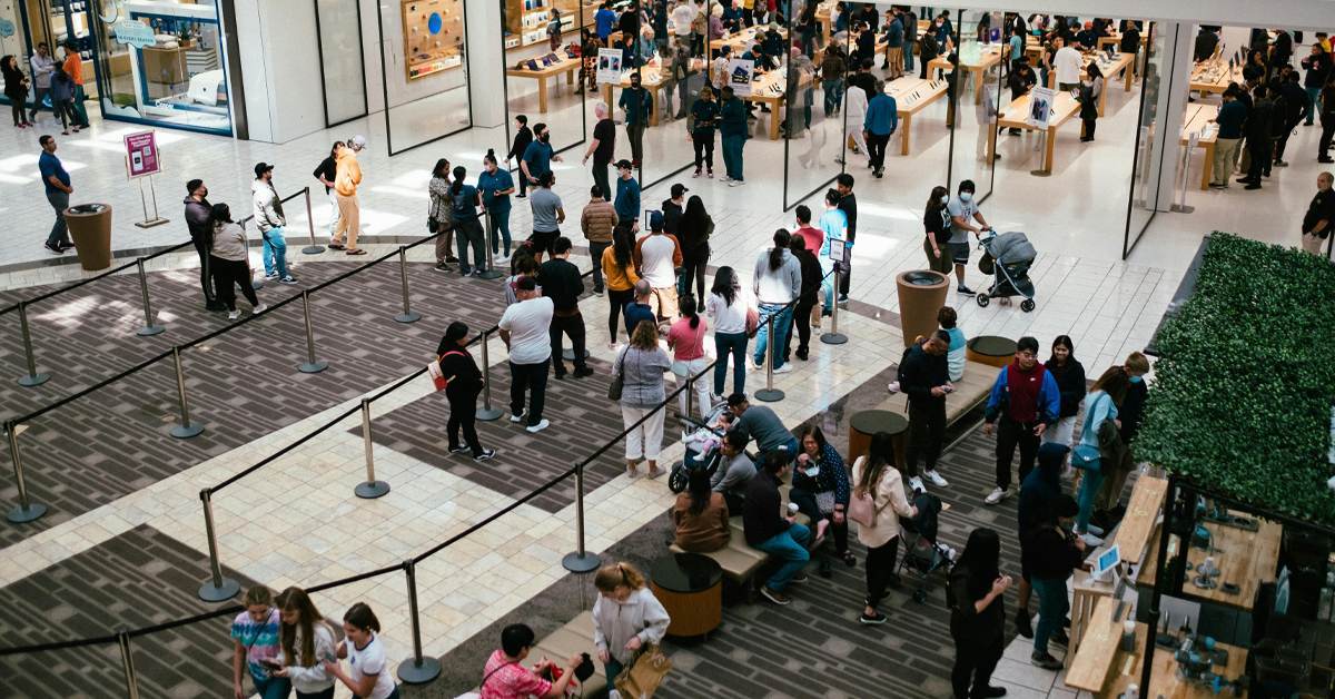 Busy shopping mall with crowds of people outside an Apple Store, showing the revival of physical retail in 2026