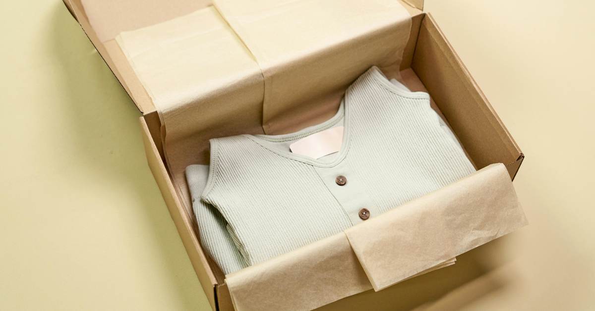 Folded clothing packed in a recycled cardboard box with tissue paper, illustrating sustainable retail packaging practices