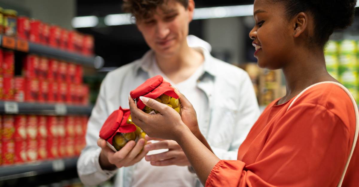 Retail store employee and customer looking at a phone and laptop together, representing in-store retail experience trends in 2026