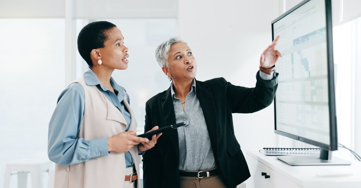 Two manufacturing professionals reviewing operational data on a screen during a knowledge transfer session
