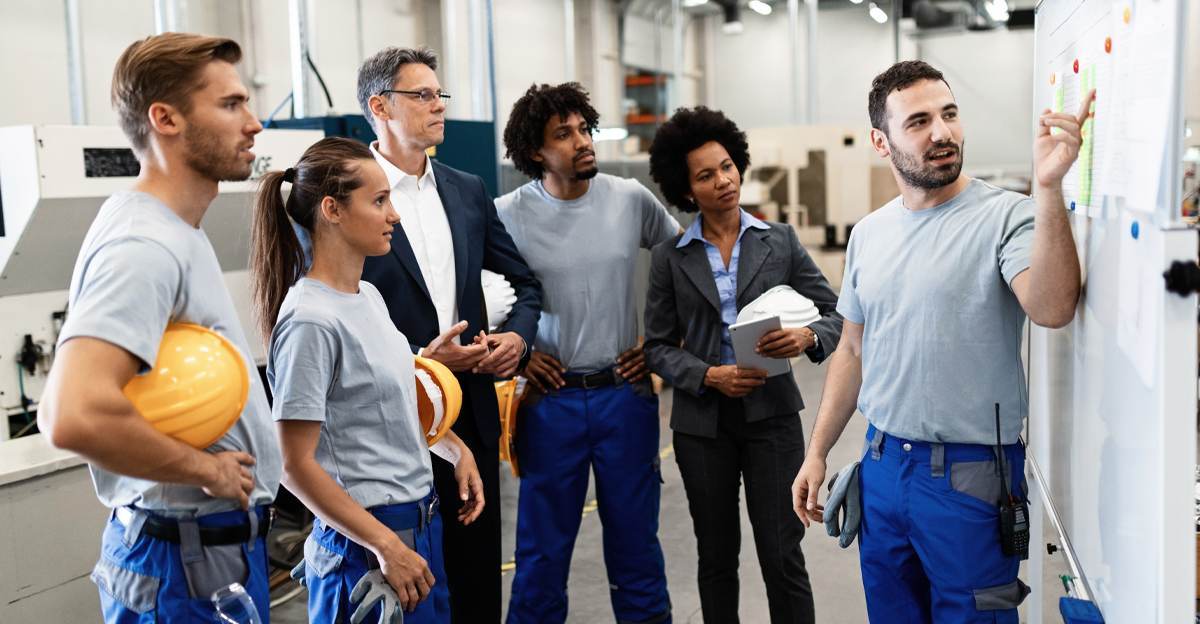 Diverse multilingual manufacturing workforce team reviewing production plans in a factory