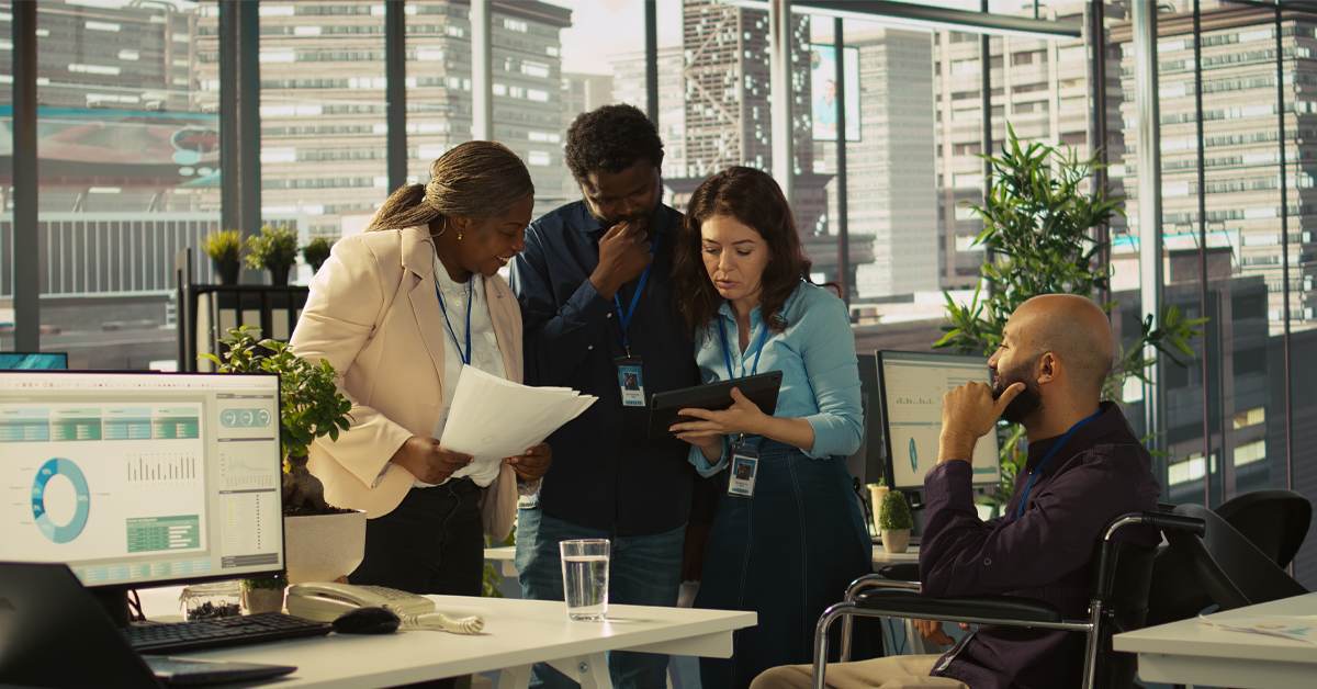 Diverse team of researchers reviewing data on a tablet and printed reports in a modern office, representing collaborative human expertise in market research