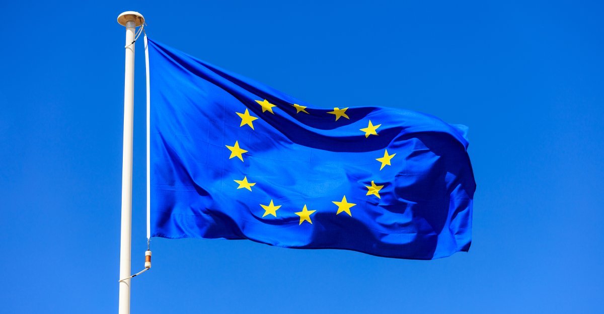EU flag flying against a blue sky, representing the single regulatory framework governing food and beverage packaging design across member states