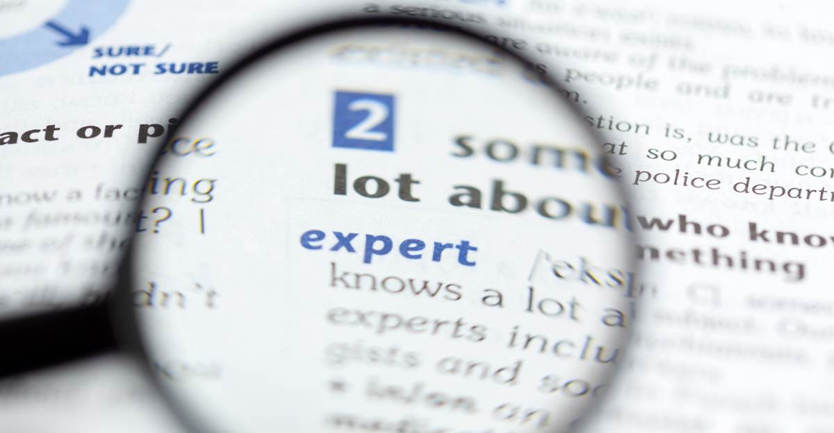 A magnifying glass focused on the word "expert" in a dictionary definition